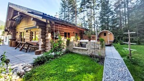 Un rustico chalet con fondamenta in pietra, rivestimento in legno e una piccola struttura in legno con tetto curvo.
