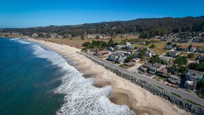 A coastal residential area with houses along the beach, a clear sky, and a hilly background. - 2 Blocks to ocean, steps to beach, ocean view,  coastal trail, BBQ (Half Moon bay)