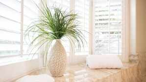 A bathroom with a large window, a textured vase with a plant, and two rolled towels on a marble ledge. - 2 Blocks to ocean, steps to beach, ocean view,  coastal trail, BBQ (Half Moon bay)
