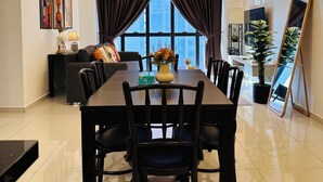 Un comedor moderno con una mesa grande, sillas, una lámpara colgante decorativa y vistas al exterior.