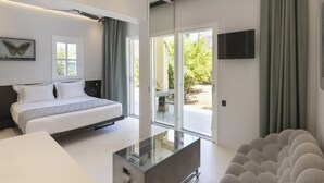 Ein modernes Schlafzimmer mit Bett, Glastisch, Fernseher und Blick ins Freie.