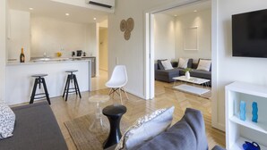 A modern living space with a kitchen, dining area, and a seating area with a sofa and chairs.