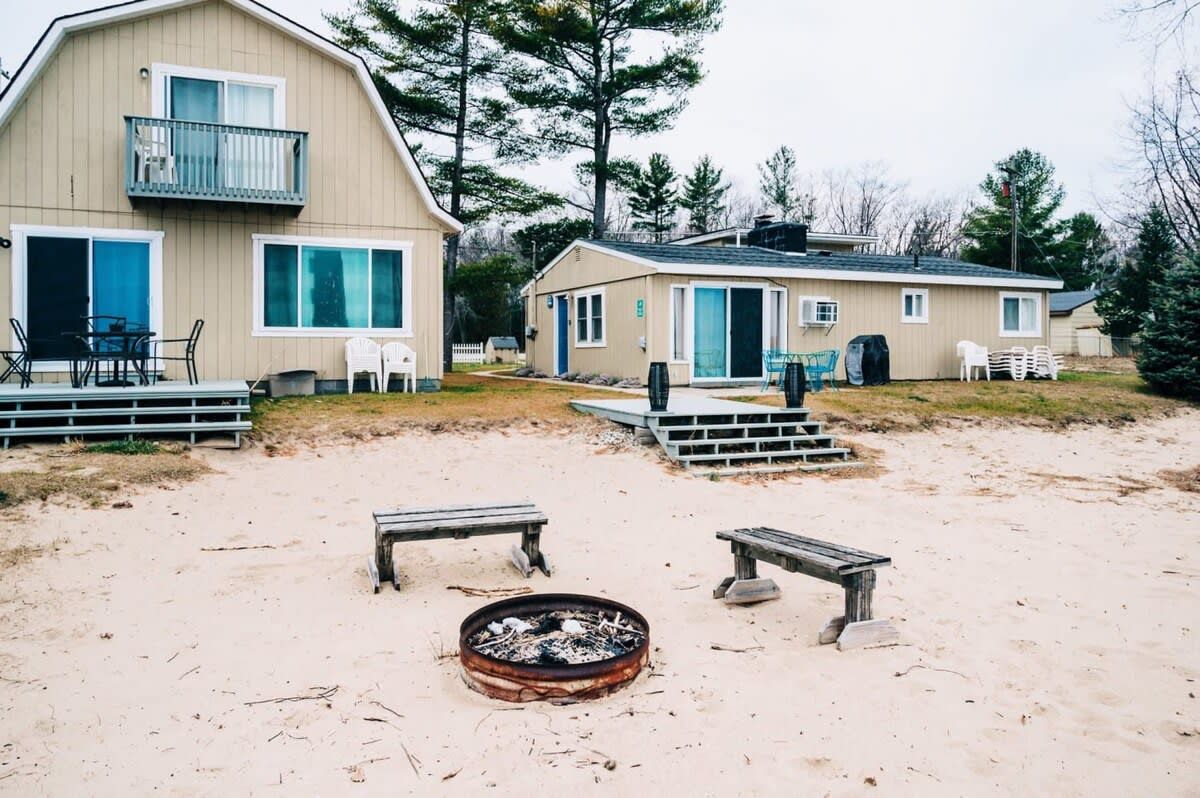 A beachside property with a large building, a smaller structure, and a fire pit area.