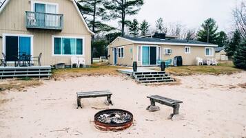 A beachside property with a large building, a smaller structure, and a fire pit area.