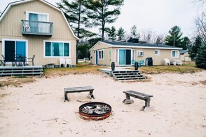 A beachside property with a large building, a smaller structure, and a fire pit area.