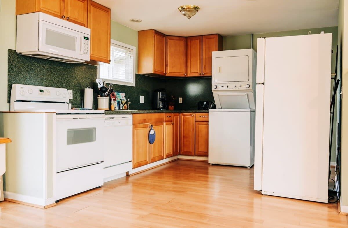 Una cocina con armarios de madera, un refrigerador blanco, un microondas, una estufa y una cafetera.