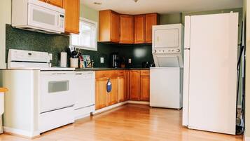 Una cocina con armarios de madera, un refrigerador blanco, un microondas, una estufa y una cafetera.
