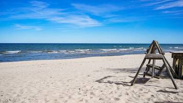 Une plage avec une échelle en bois et une petite structure en bois, probablement une table ou un banc, sur le sable.