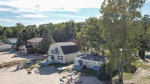Ein Strandhaus mit einer großen Terrasse, einem Pool und einer überdachten Veranda.