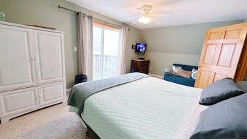 A bedroom with a bed, a wardrobe, a television, and a door.