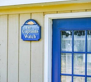 A sign reading "The Captains Watch" mounted on a wooden wall.