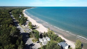 Luftaufnahme einer Küstenlandschaft mit Strand, Häusern und einer Straße.