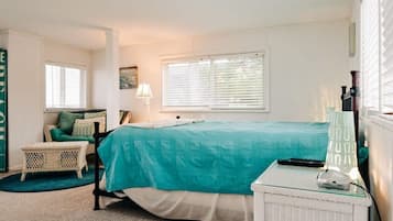 Ein Schlafzimmer mit einem Bett, einem Sessel, einer Lampe und einem kleinen Tisch mit Fernbedienung.