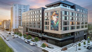 A modern hotel with a large mural on the facade, a spacious entrance area, and a parking lot with cars. - Hotel Celare, Cincinnati Midtown, a Tribute Portfolio Hotel (Cincinnati)