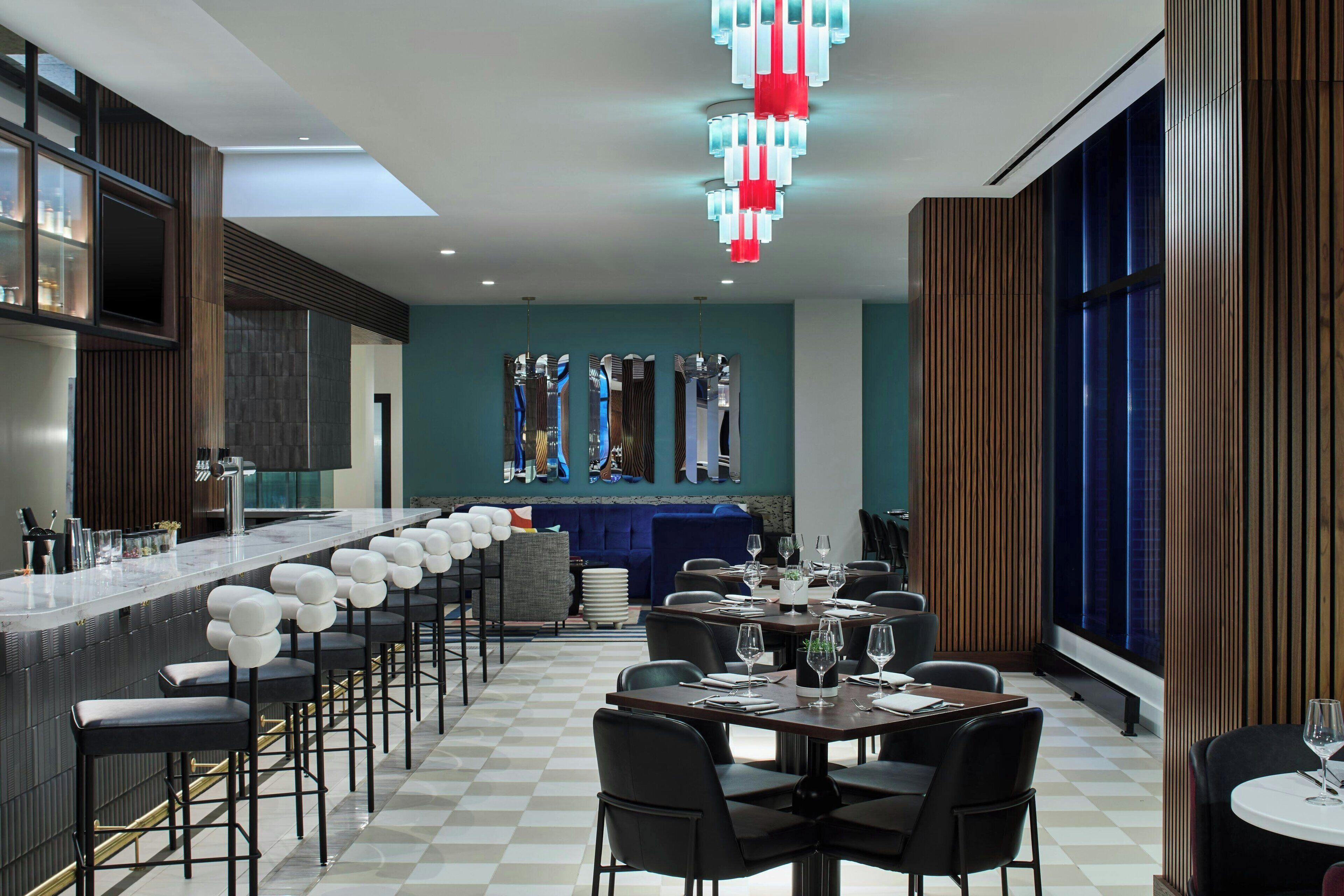 A modern bar area with a long counter, multiple bar stools, and a blue sofa.