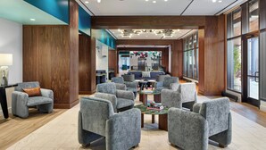 A modern lobby with grey upholstered seating, wooden paneling, and large windows. - Hotel Celare, Cincinnati Midtown, a Tribute Portfolio Hotel (Cincinnati)