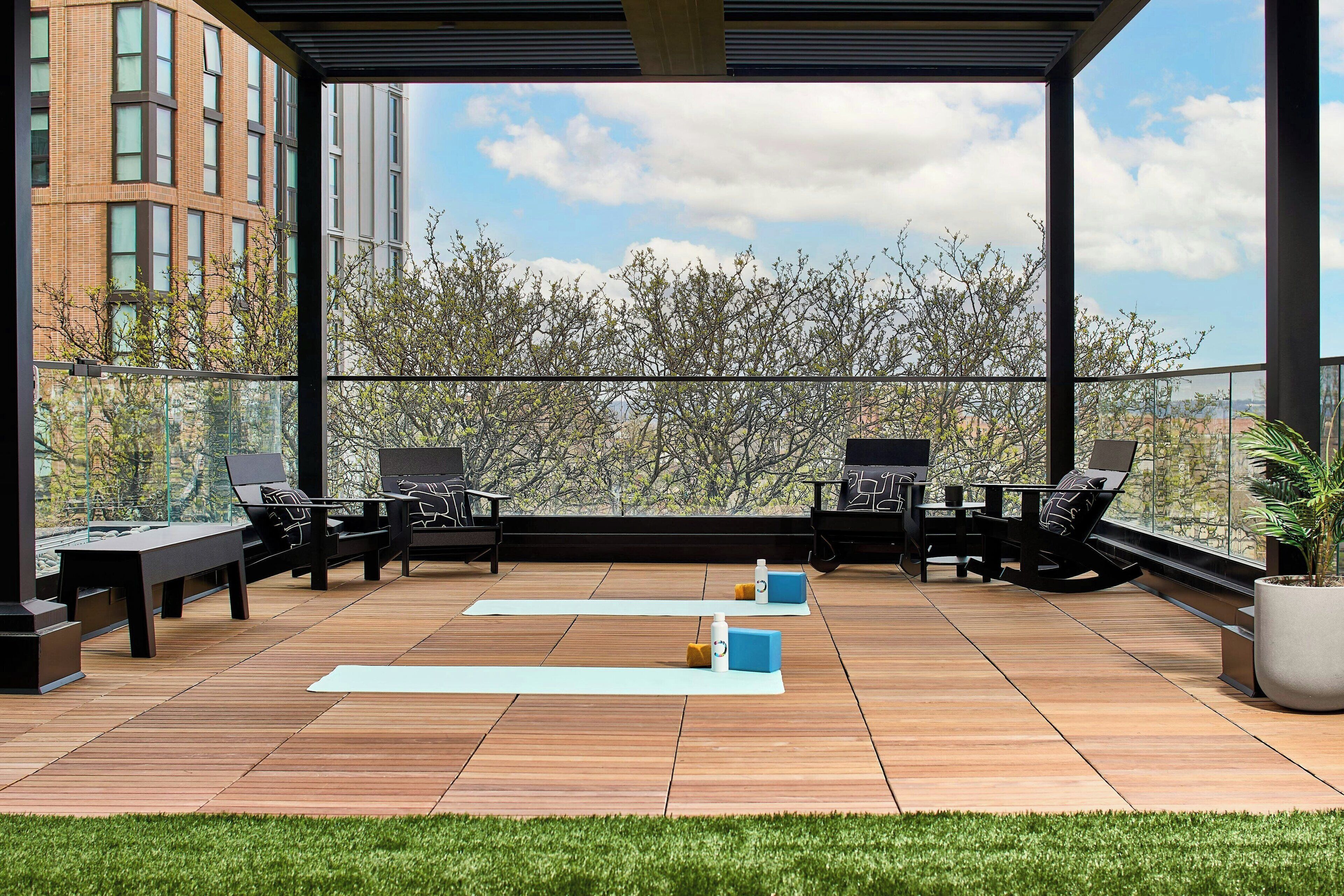 A rooftop terrace with outdoor seating, yoga mats, and a potted plant.