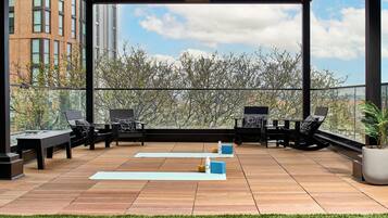 A rooftop terrace with outdoor seating, yoga mats, and a potted plant.