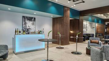 A modern lounge area with a bar, seating, and a large abstract painting.