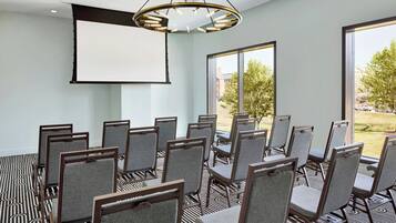 A conference room with a large screen, multiple chairs, and a patterned carpet.