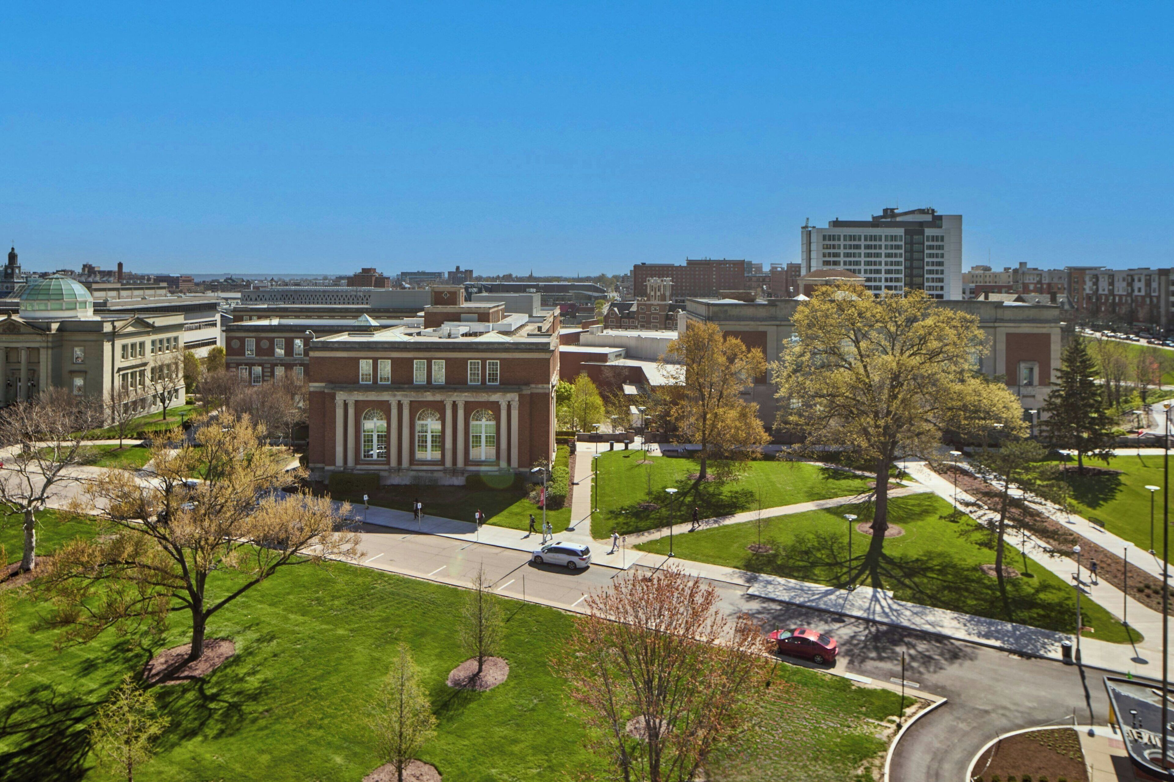 Un campus qui se distingue par un bâtiment imposant doté de grandes fenêtres et d’un dôme, entouré de pelouses verdoyantes et d’arbres.