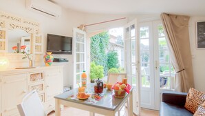 A bright kitchen with a dining table, a sofa, and a TV. - Le Mimosa St Laurent by Interhome (Gassin)
