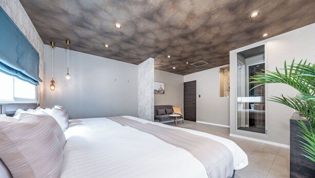 A modern bedroom with a large bed, a sofa, and a plant. - JAPAVISTA Dusk (Osaka)