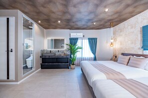 A modern hotel room with a large bed, a built-in desk, a bathroom with a toilet and sink, and a ceiling with recessed lighting.