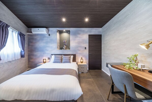 A modern bedroom with a bed, bedside lamps, a desk, and a wall-mounted air conditioner.