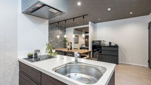 A modern kitchen with a large island, stainless steel sink, and dark wood cabinetry. - JAPAVISTA Dusk (Osaka)