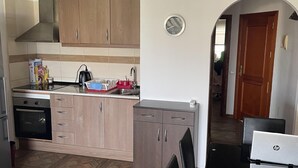 A kitchen with wooden cabinets, a stove, and a dining area with a table and chairs. - Tropical Bliss Escape in Costa Adeje (Adeje)