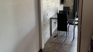 A hallway with a brick wall, a black chair, and a TV mounted on the wall. - Tropical Bliss Escape in Costa Adeje (Adeje)