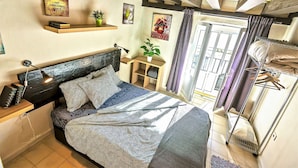 A bedroom with a bed, bedside tables, a nightstand, a potted plant, and a window with curtains.