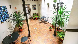 An outdoor patio with tiled flooring, metal chairs, a small round table, and potted plants.
