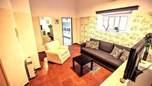A living room with a sofa, a chair, a coffee table, and a window with floral wallpaper. - Milagros #4, two-bedroom Central Apartment (El Puerto de Santa María)