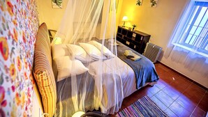 A bedroom with a bed, a bedside table, a lamp, a radiator, and a window with curtains. - Milagros #4, two-bedroom Central Apartment (El Puerto de Santa María)