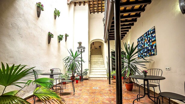 A courtyard with tiled flooring, potted plants, outdoor seating, and a staircase leading to an upper level. - Milagros #3, three-bedroom Central Apartment (El Puerto de Santa María)