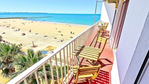 Un balcón con sillas de madera que da a una playa.