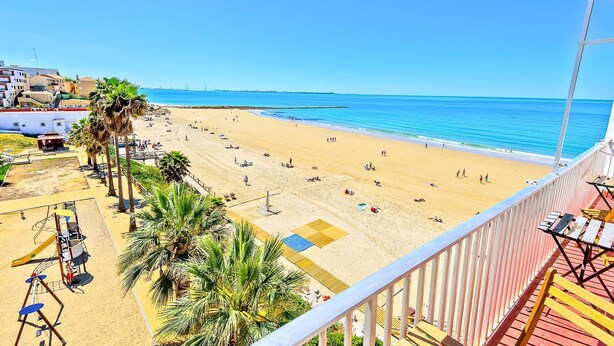 Una playa con palmeras, un parque infantil y vistas al océano.