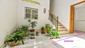 A spacious indoor area with a staircase, potted plants, and a window with bars.