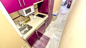 A compact kitchen with a microwave, sink, and two stovetops.
