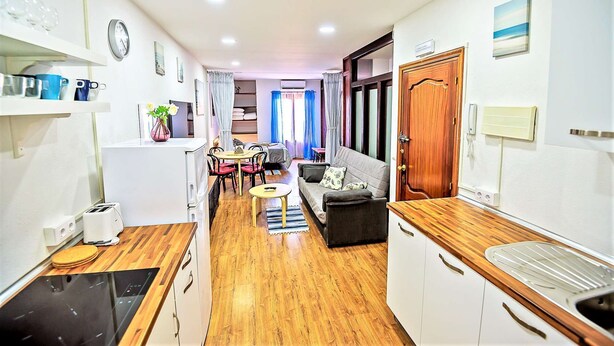 A compact hotel room with a kitchenette, a dining area, and a living space.