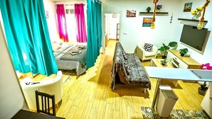 A compact living space with a bed, a sofa, a TV, and a desk.