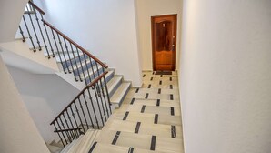 A staircase with a wooden handrail and black balusters, leading to a wooden door with a number '1' above it.