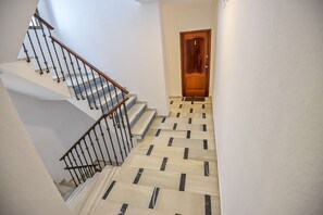 Staircase with a geometric pattern, featuring white and black tiles, a wooden handrail, and a black metal baluster.