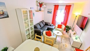 Moderni olohuone, jossa on sohva, nojatuoleja, ruokapöytä ja televisio.
