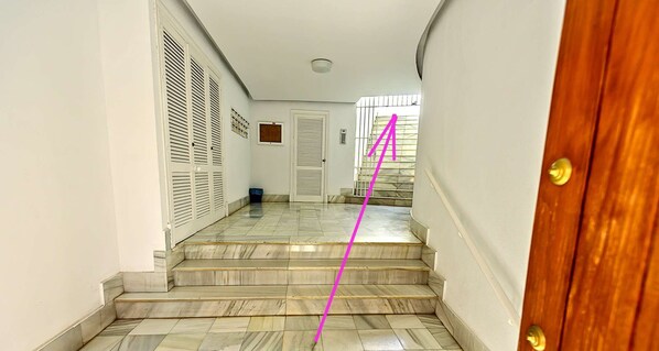 A hallway with marble flooring leading to a wooden door.