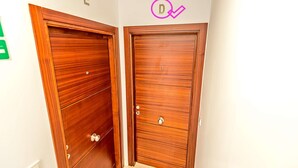 Two wooden doors with a small window on the left door and a circular sign above the right door. - Plaza Herrería Central Apartment "D" with Terrace. Right downtown, best location (El Puerto de Santa María)