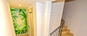 A staircase with a wooden handrail and a low ground floor plant.