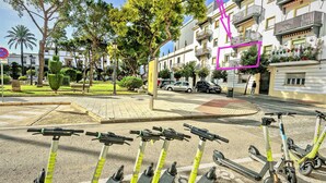 A street with parked scooters, a pedestrian path, and residential buildings. - Plaza Polvorista 4-Bedroom Apartment with Balcony in front of the beautiful park (El Puerto de Santa María)